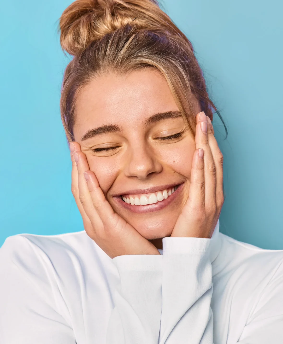 A smiling woman resting her face in her hands.